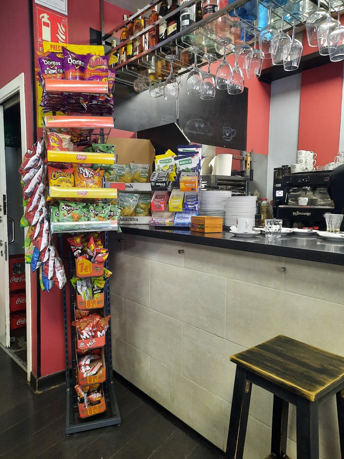 Barra de la cafetería con cafetera, copas colgadas y expositor de aperitivos